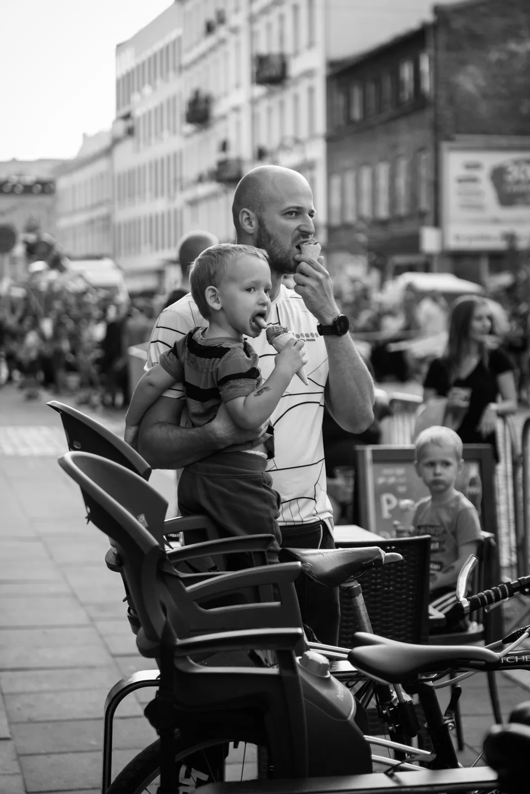 Adult holding a child beside outdoor cafe chairs