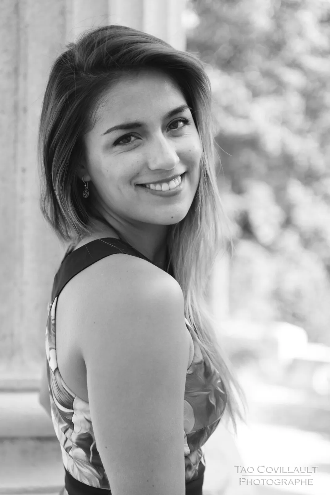 Black-and-white photograph: portrait of a woman in a floral dress outdoors.