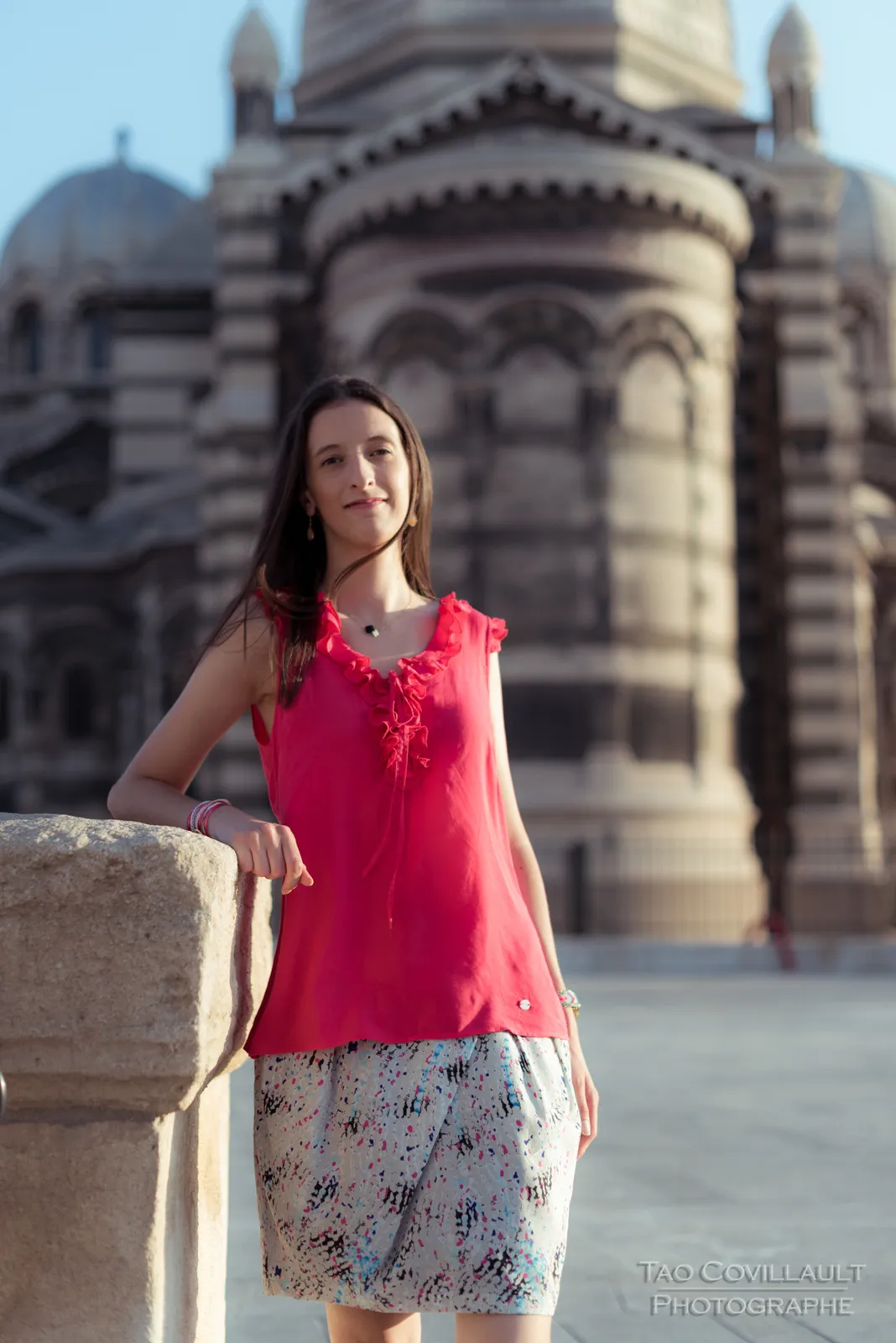 Woman in a bright pink top posing outside an ornate domed stone building.