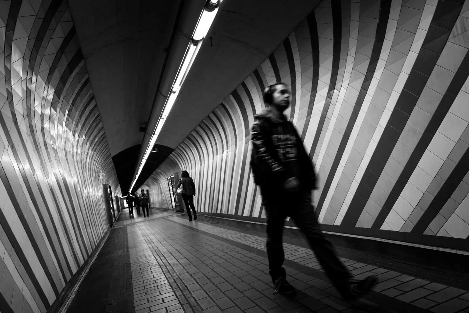 Pedestrian crossing a striped underground passage in black and white
