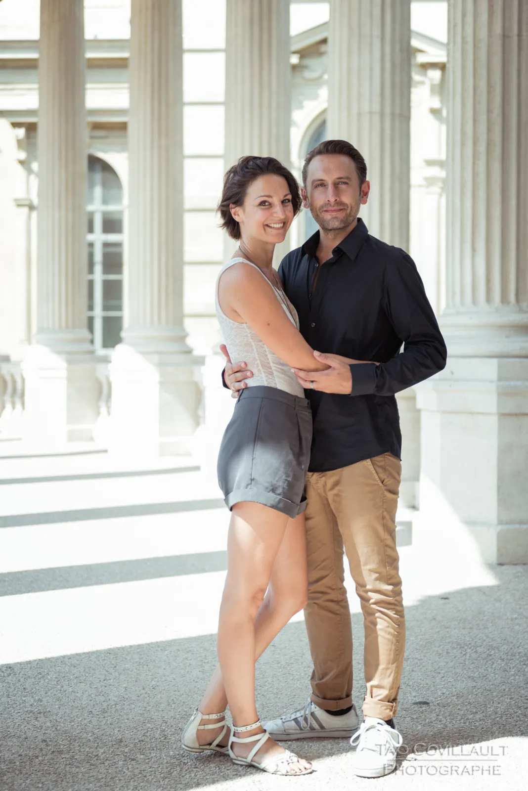Couple embracing and posing among stone columns.