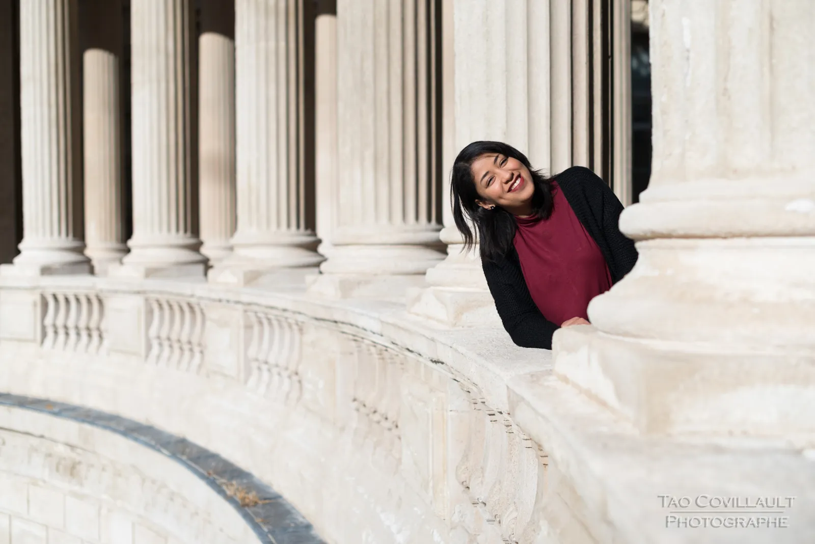 Woman leaning over a carved stone balustrade.