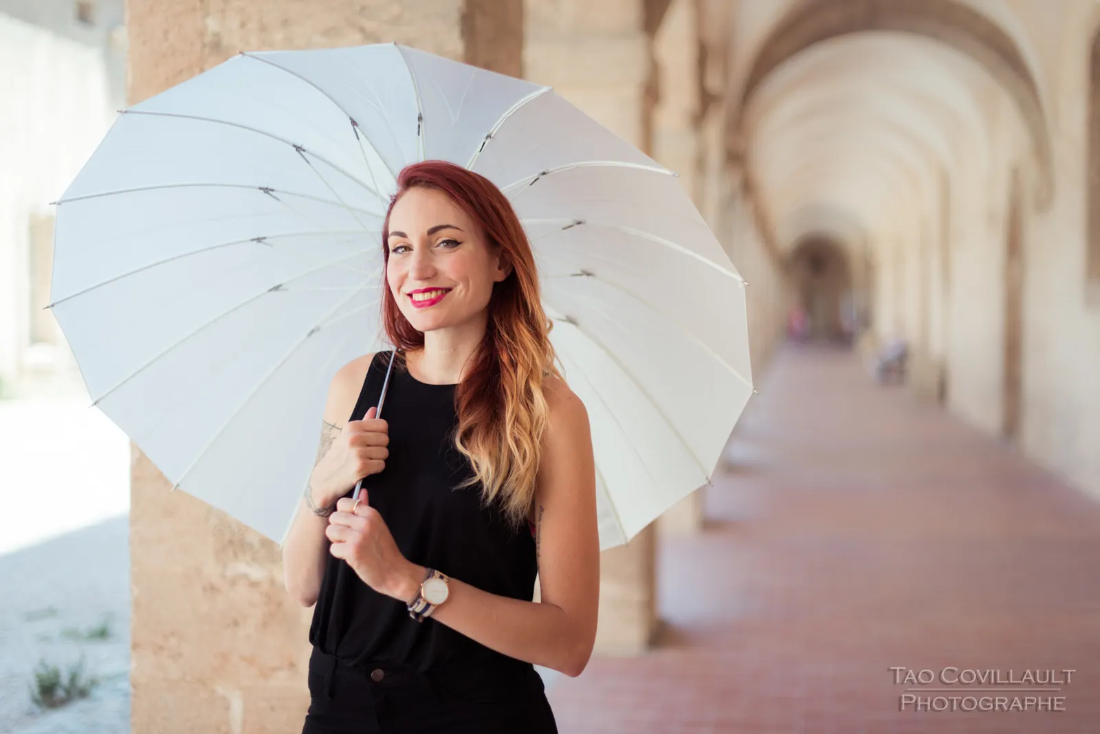 Woman in black clothing holding a white parasol.
