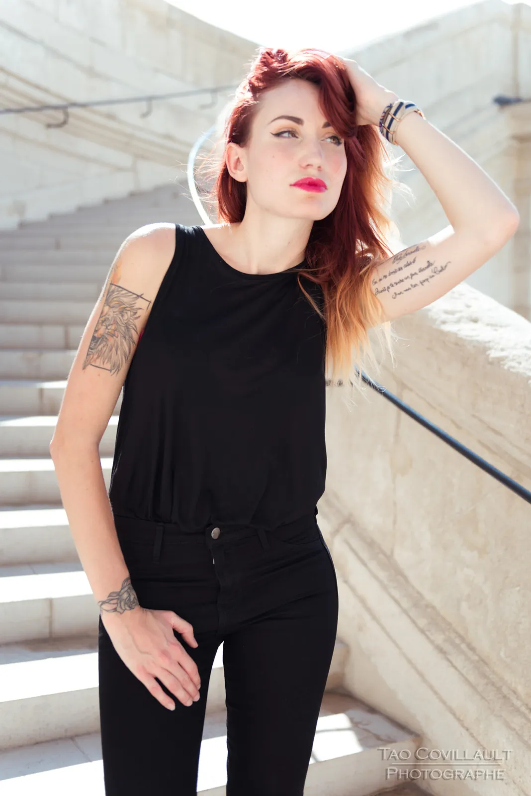 Woman in black clothing posing on pale stone steps.