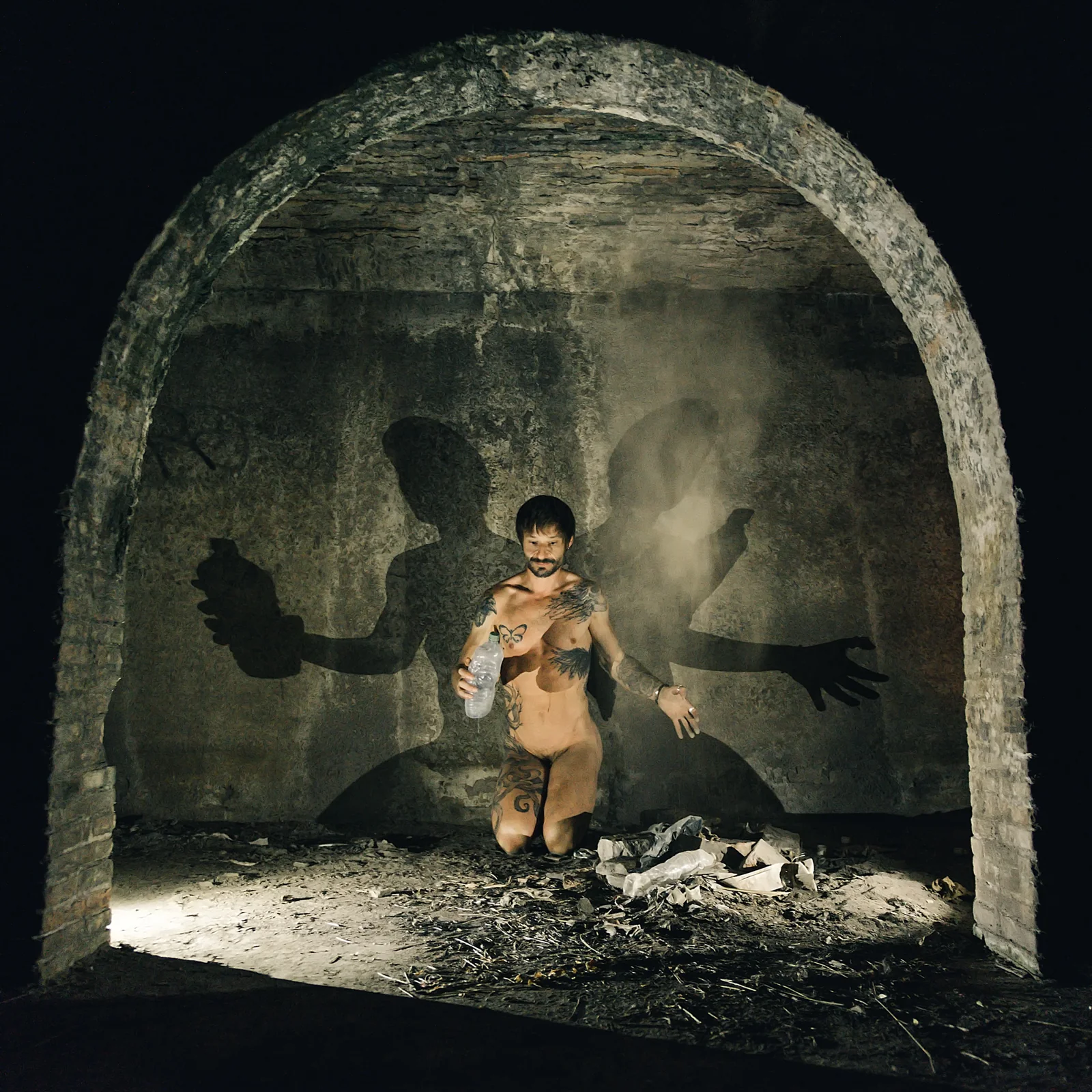 Figure kneeling inside an arched alcove with enlarged shadows