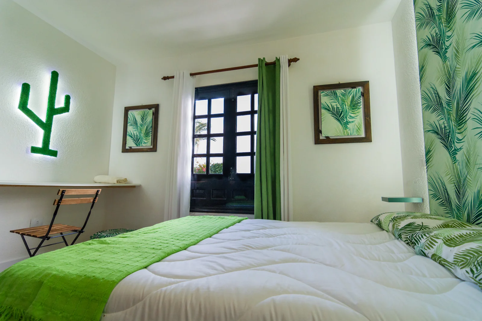 Green bedroom with a cactus wall decoration.