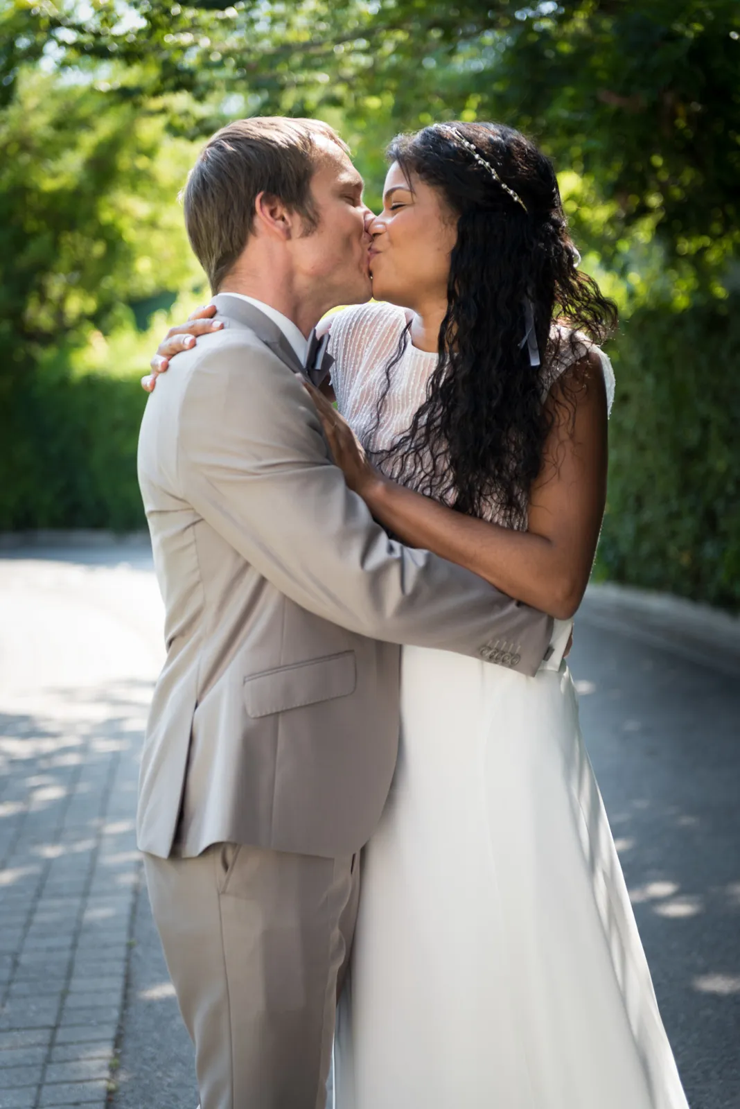 Newlyweds kissing in a leafy garden.