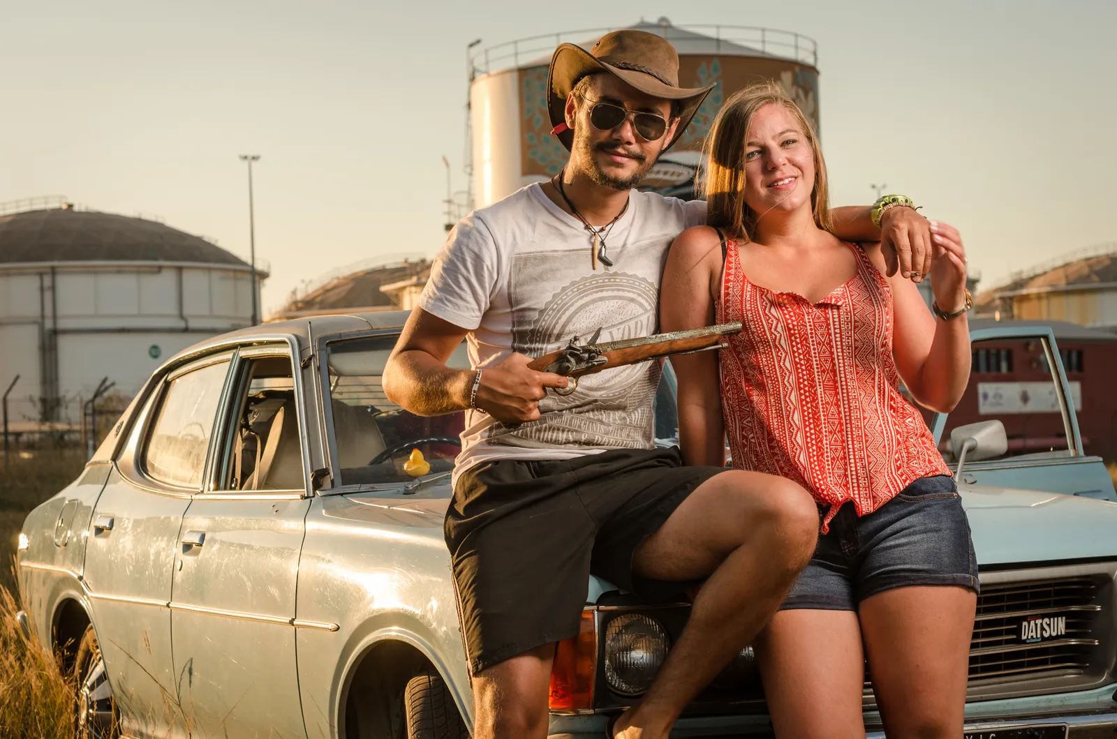 Two people posing together beside a vintage car