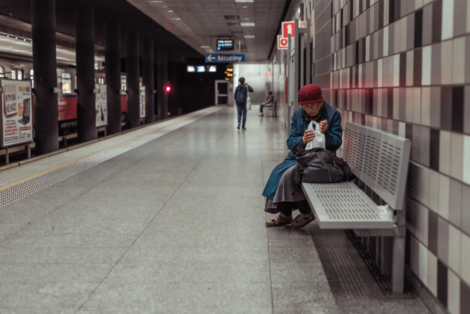 Passenger in a red hat seated on a station bench