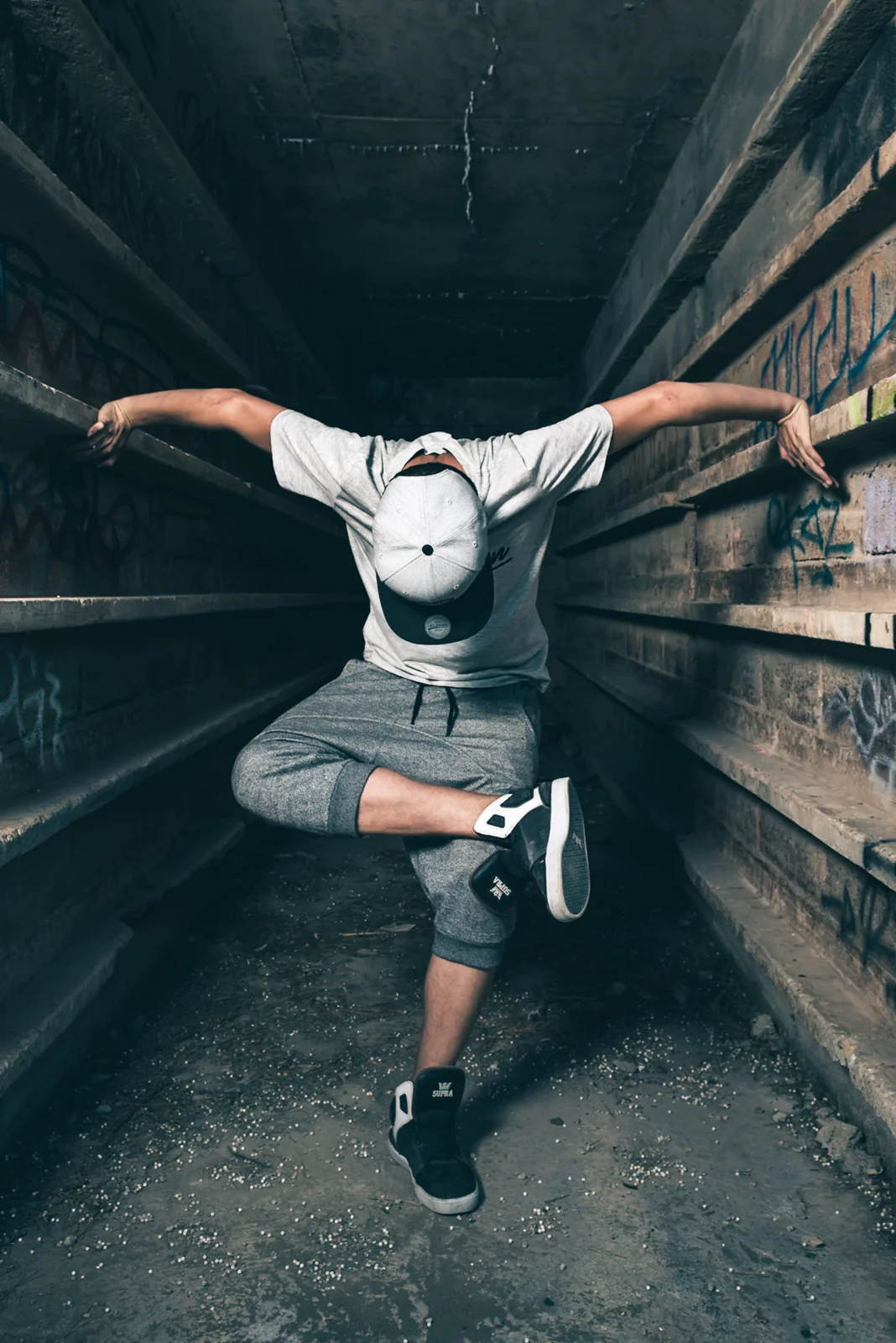 Street dancer jumping between industrial walls.