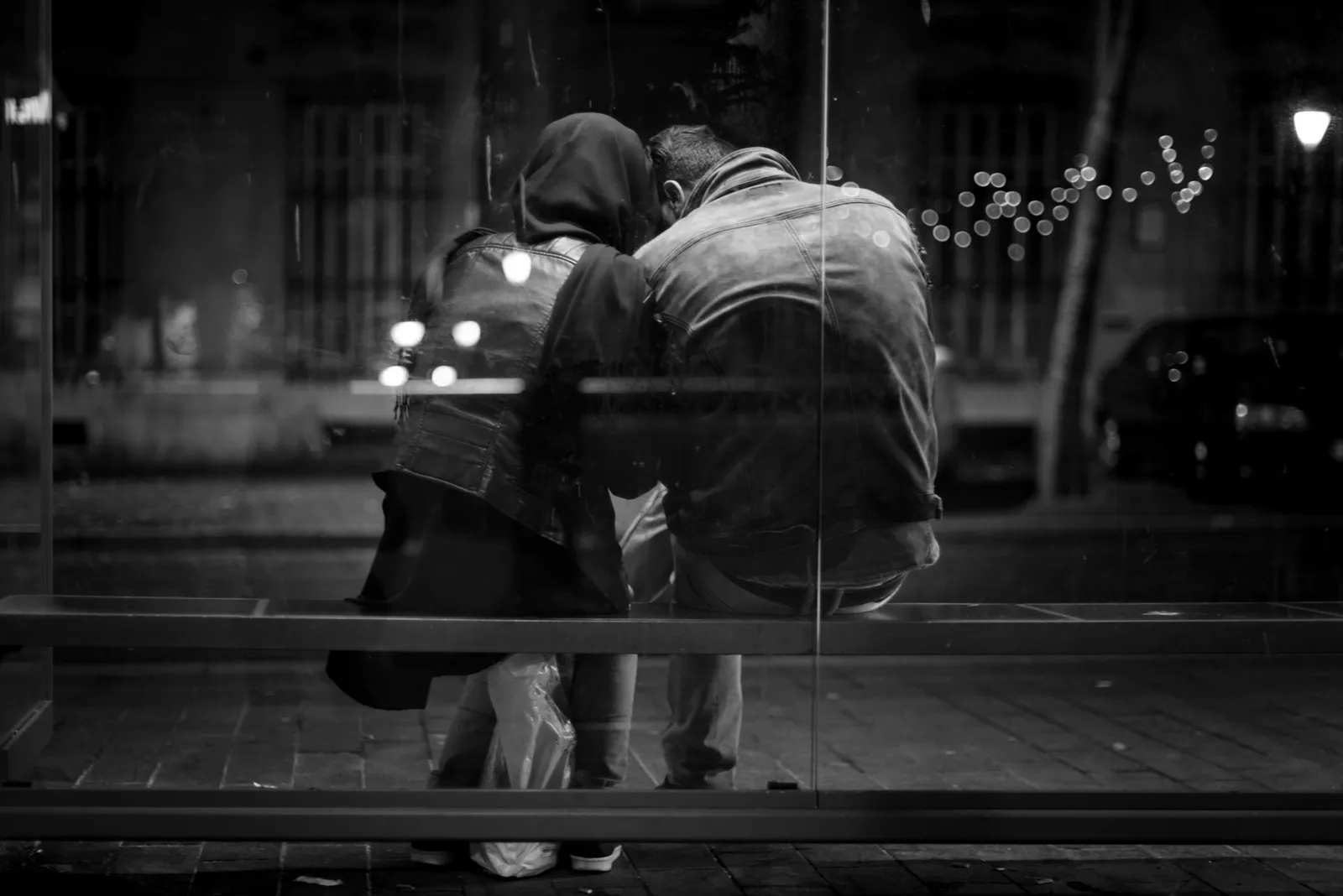 Two people reflected in dark glass at night