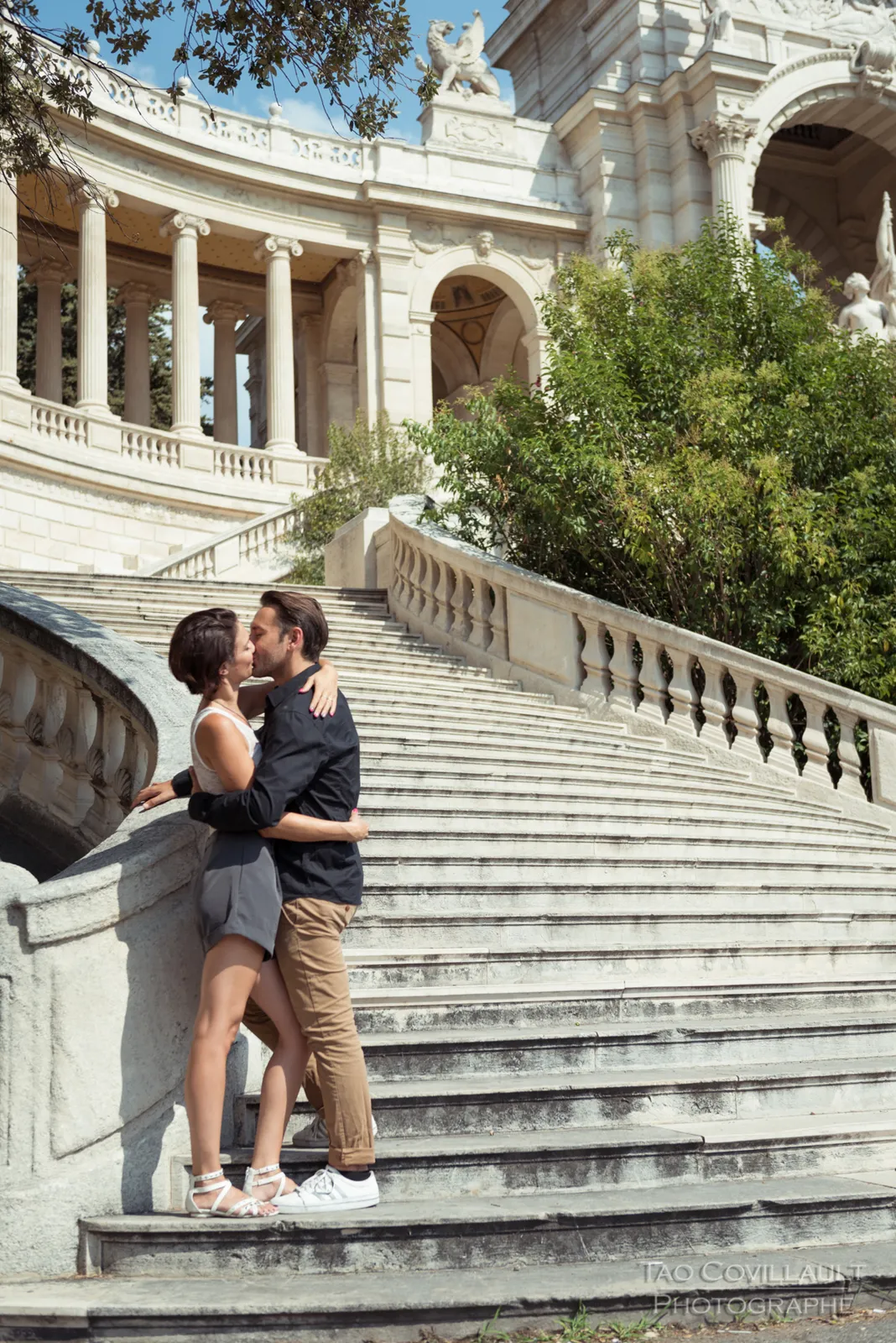 Couple embracing on a broad stone staircase.