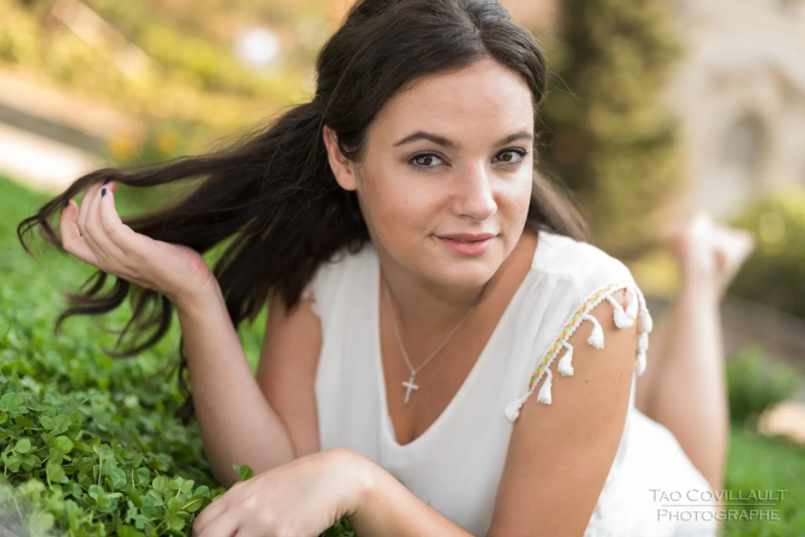 Woman in a white dress relaxing on grass.