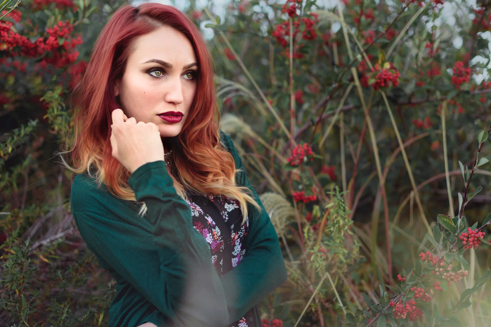 Red-haired woman standing among flowering branches.