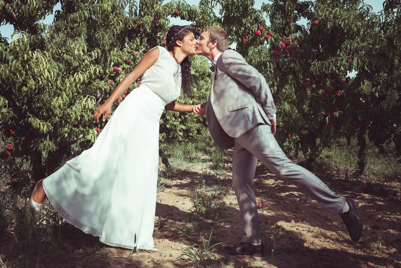 Playful wedding kiss in a garden.