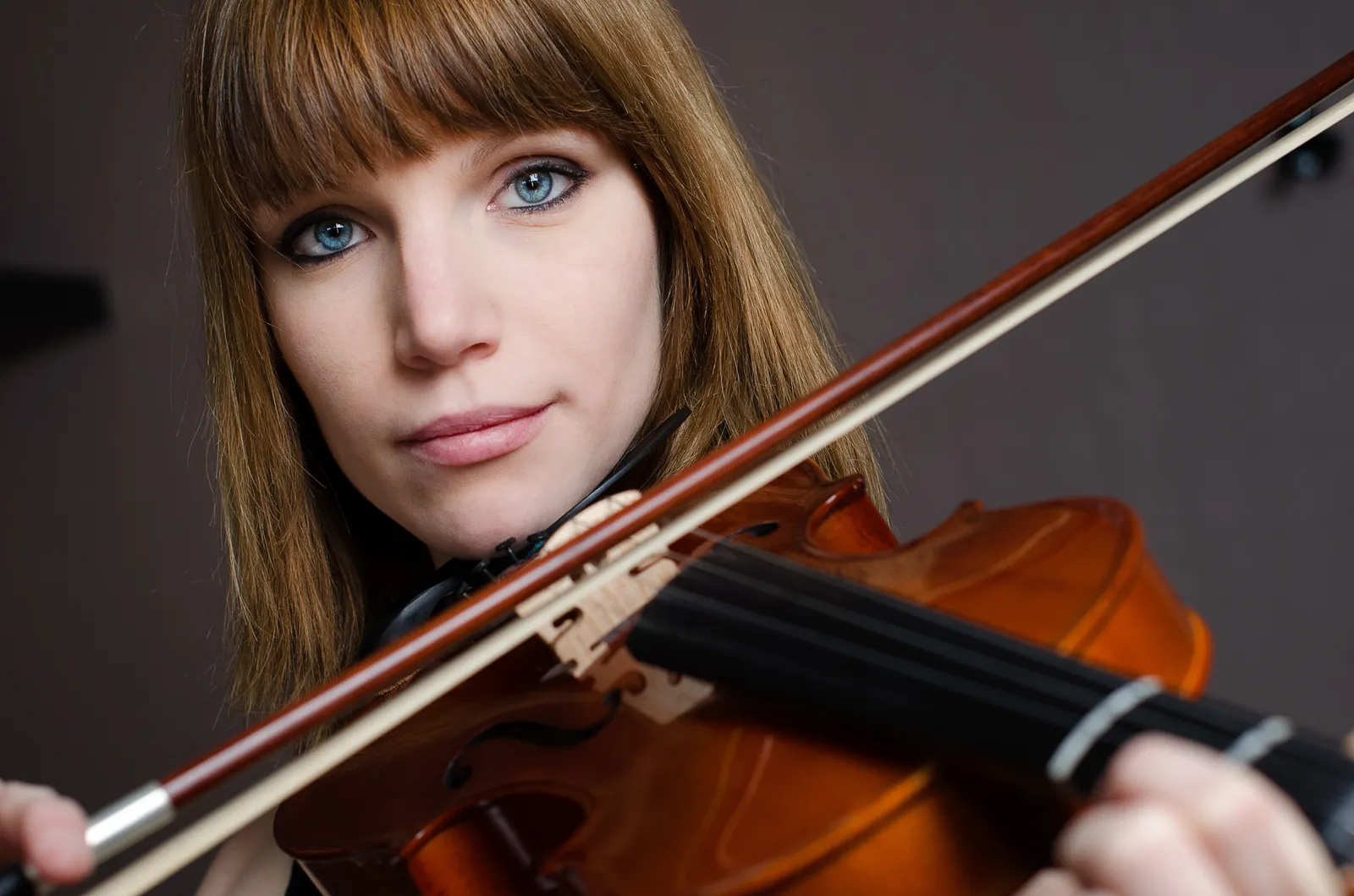 Woman holding a violin beneath her chin.