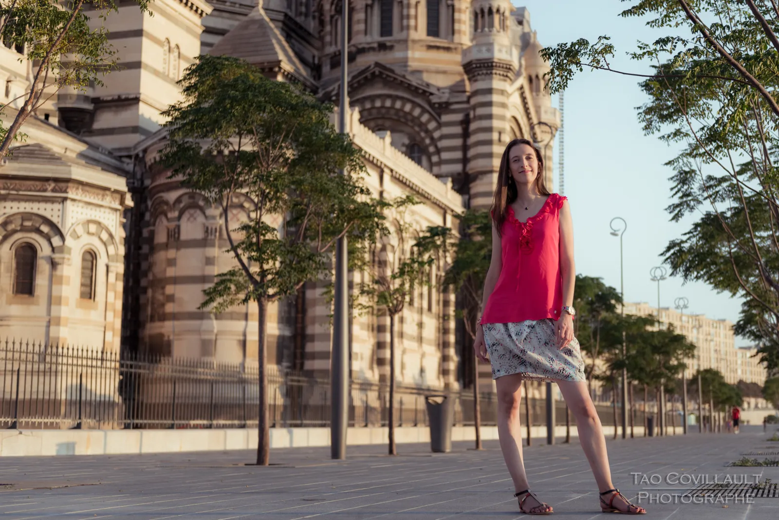Woman in a bright pink top posing outside an ornate domed stone building.