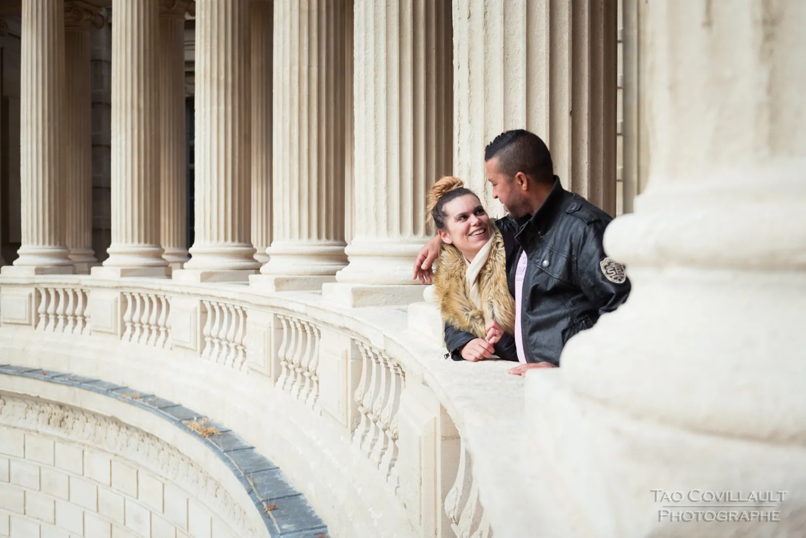 Couple posing beside a curved stone balustrade.