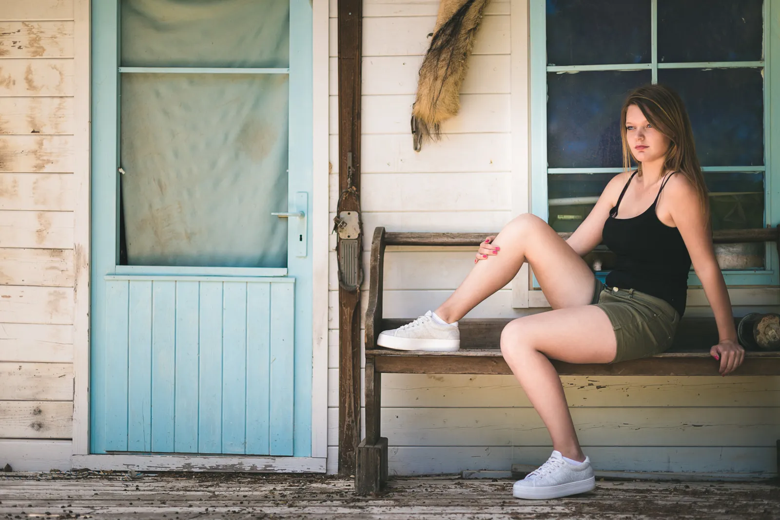 Woman seated outside a building beside a blue door.