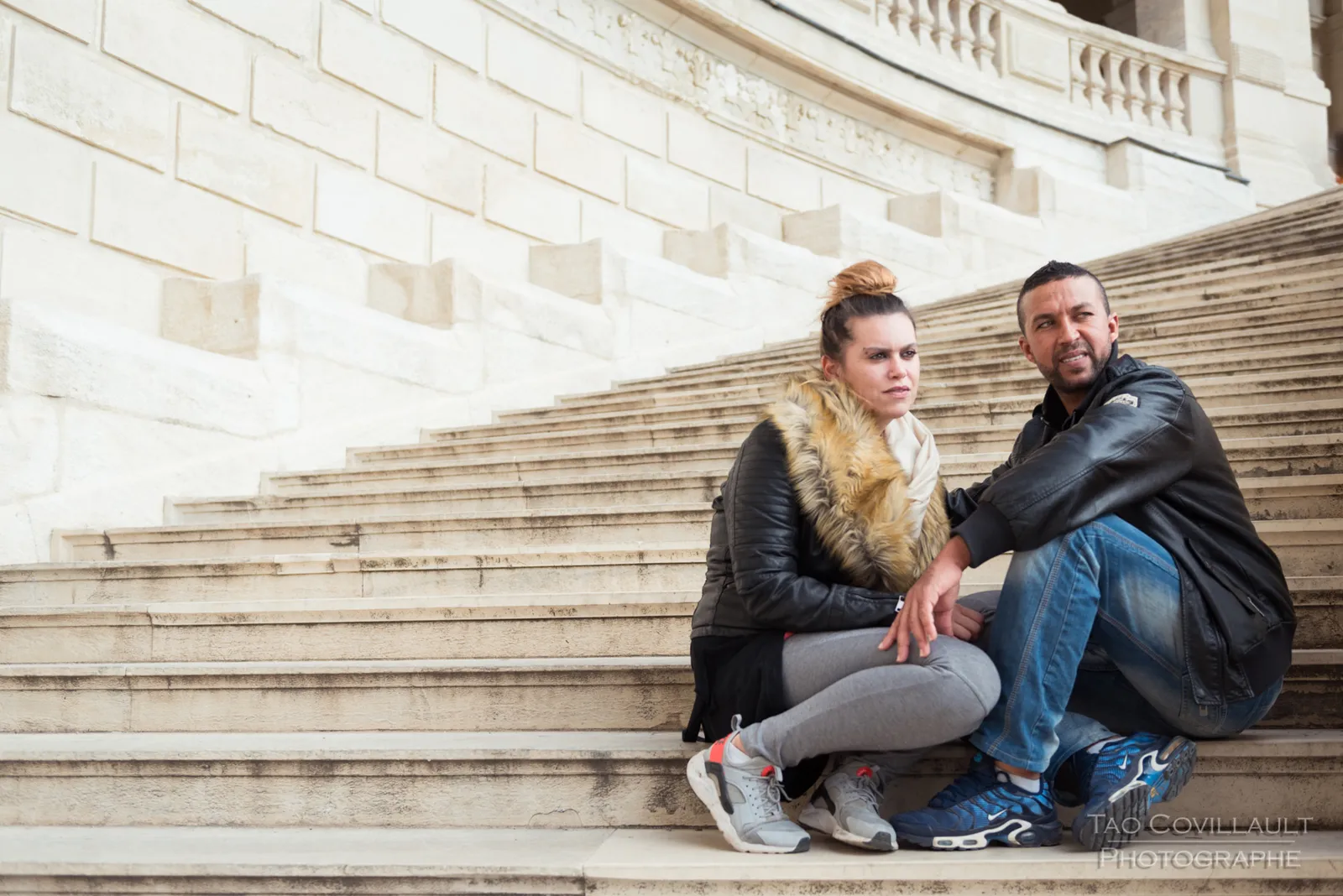 Couple sitting together on a broad stone staircase.