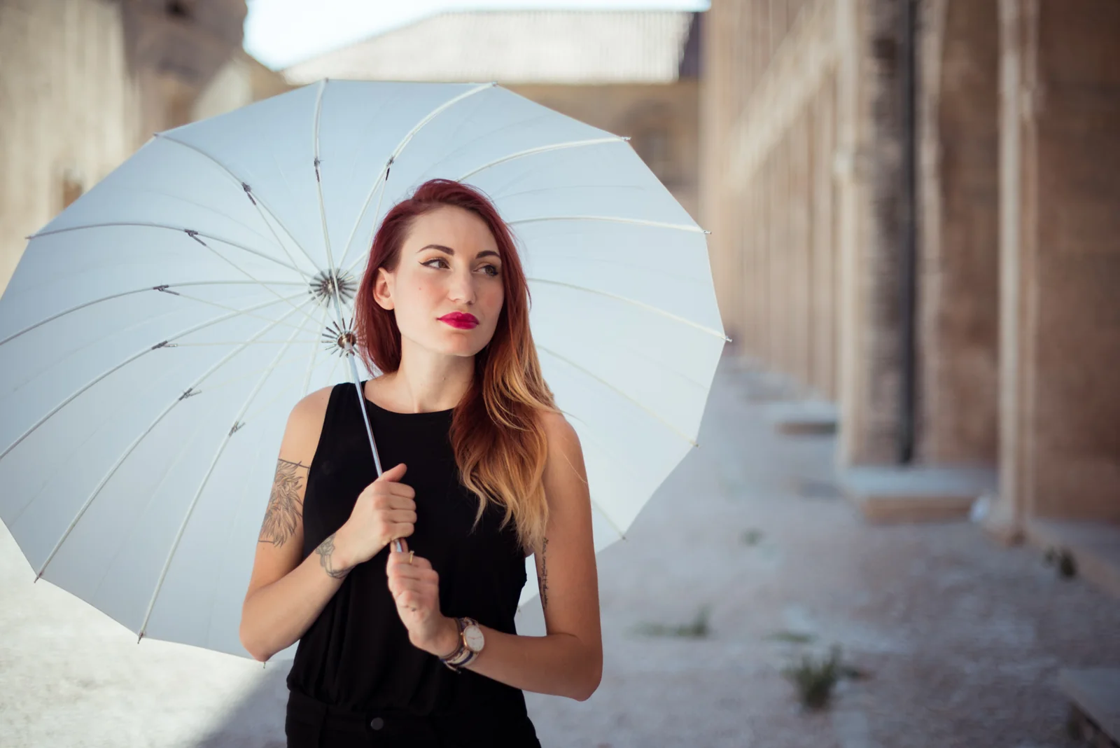 Woman in black clothing holding a white parasol.