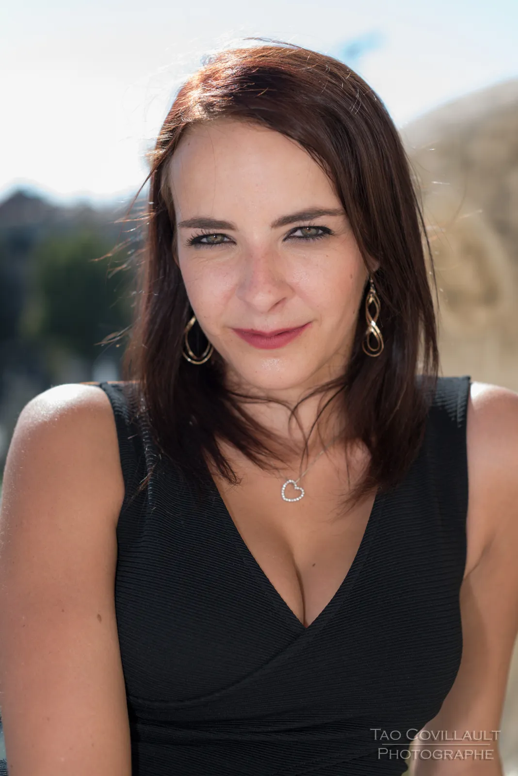Woman in a black dress posing beside a stone balustrade.