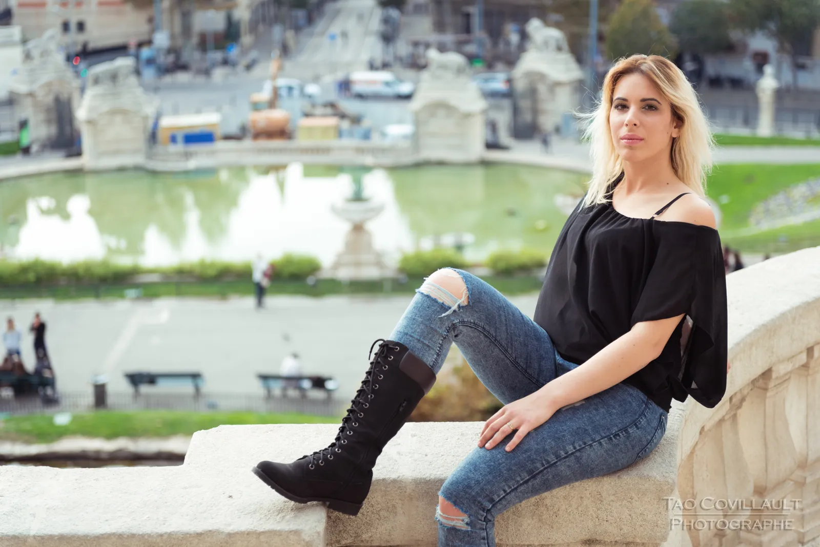 Woman in a black top and jeans posing on a stone terrace and steps.