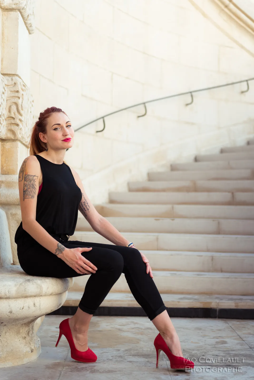 Woman in black clothing posing on pale stone steps.