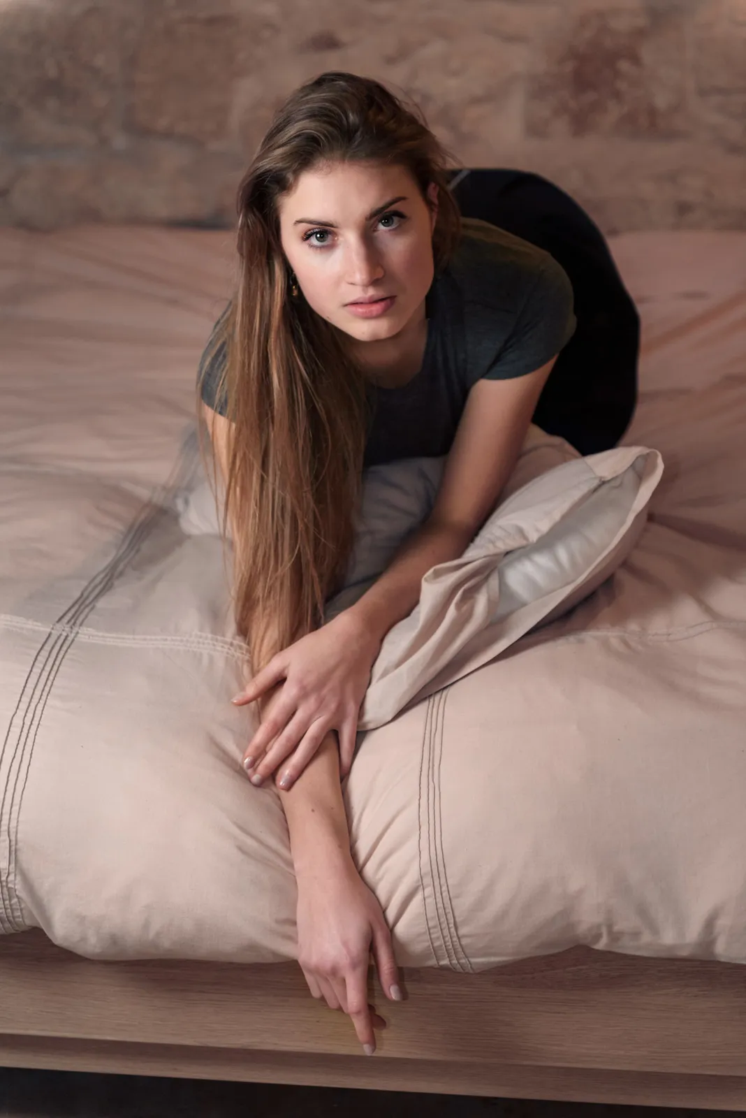 Woman leaning forward on a bed.