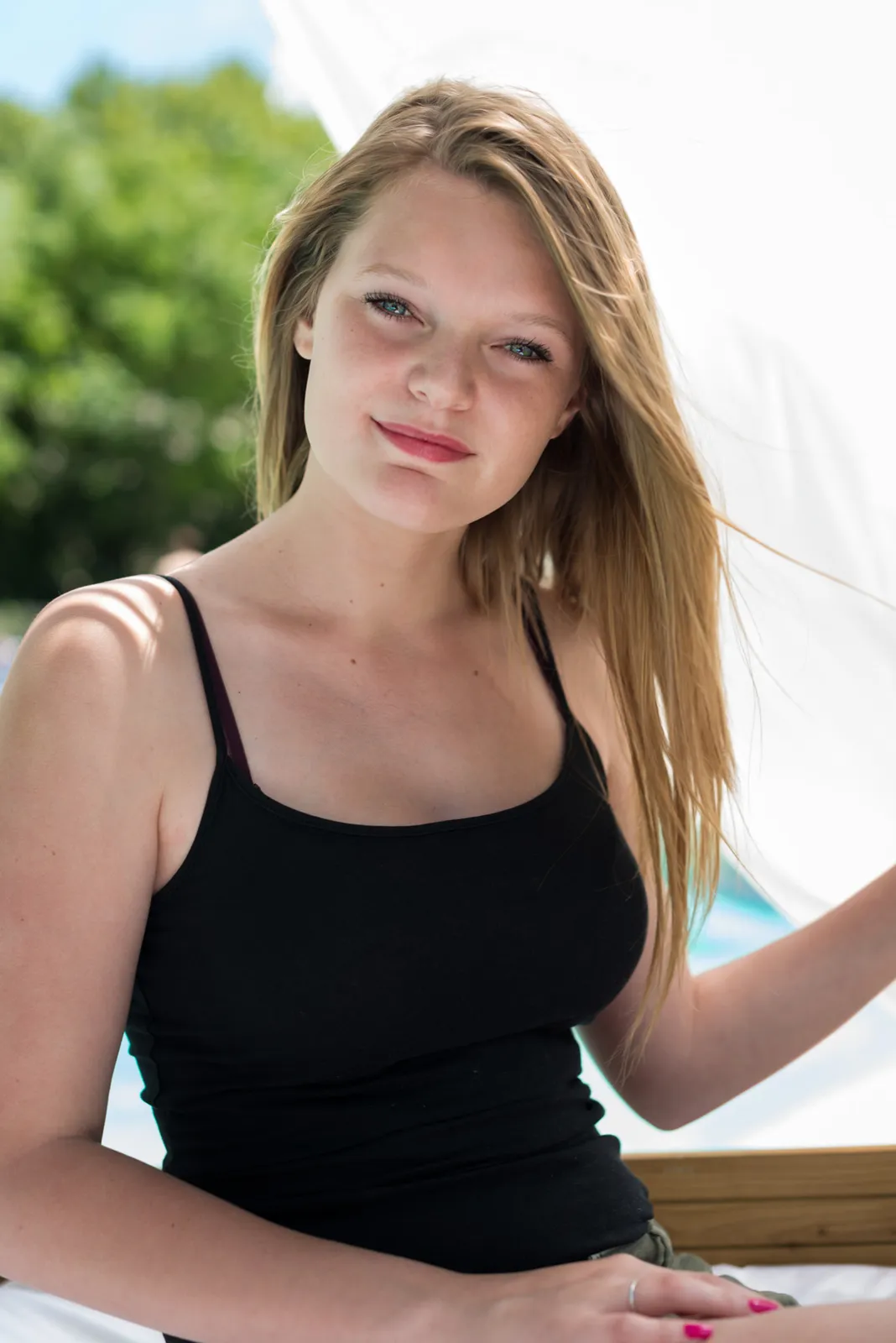 Woman in a black sleeveless top seated outdoors.