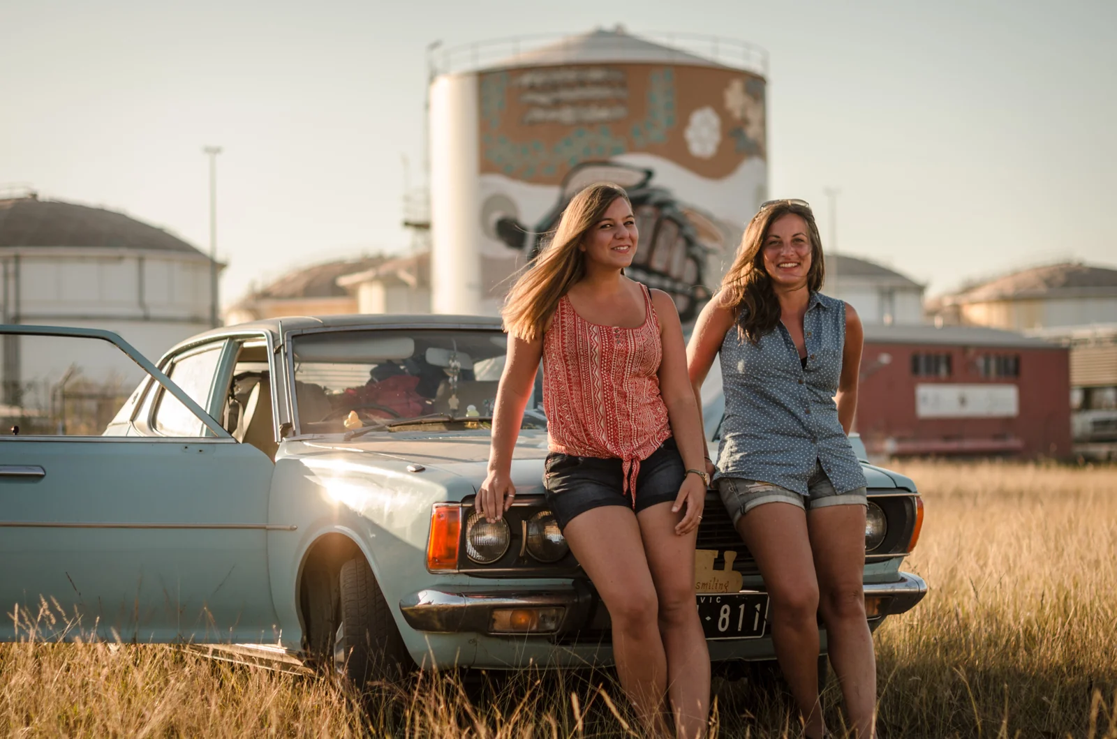 Two people seated on the front of a vintage car