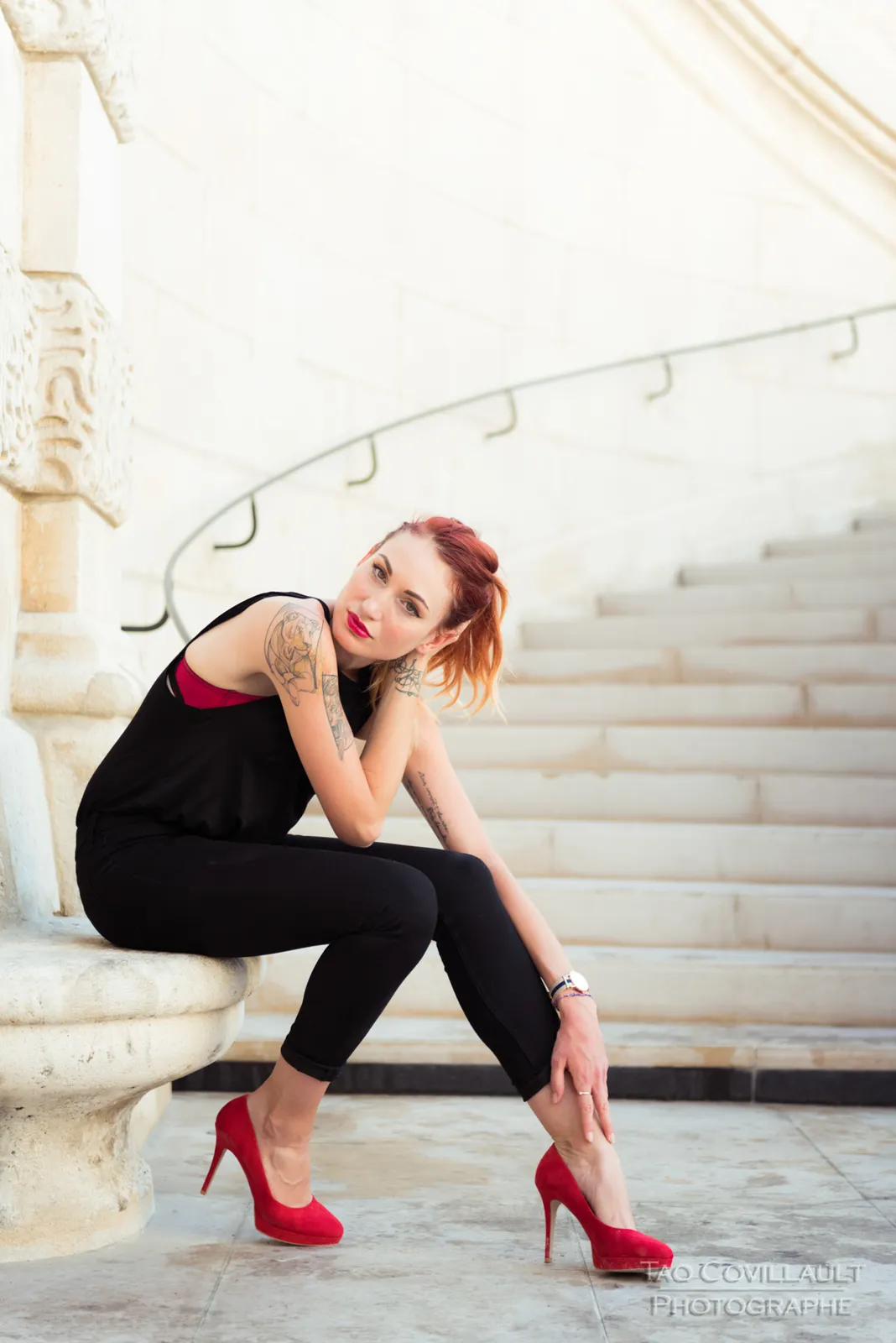 Woman in black clothing posing on pale stone steps.