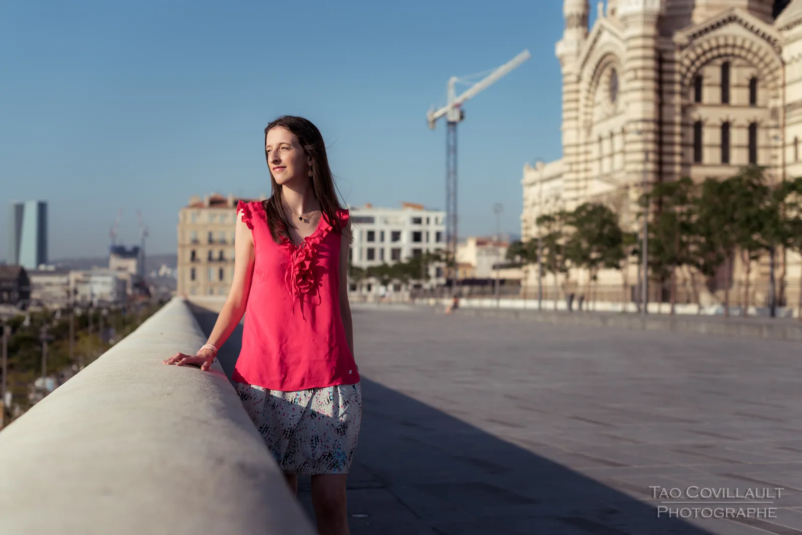 Woman in a bright pink top posing beside broad stone steps.
