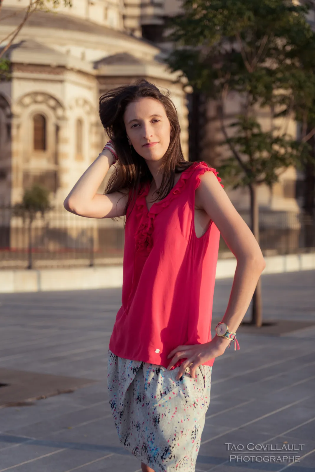 Woman in a bright pink top posing outside an ornate domed stone building.