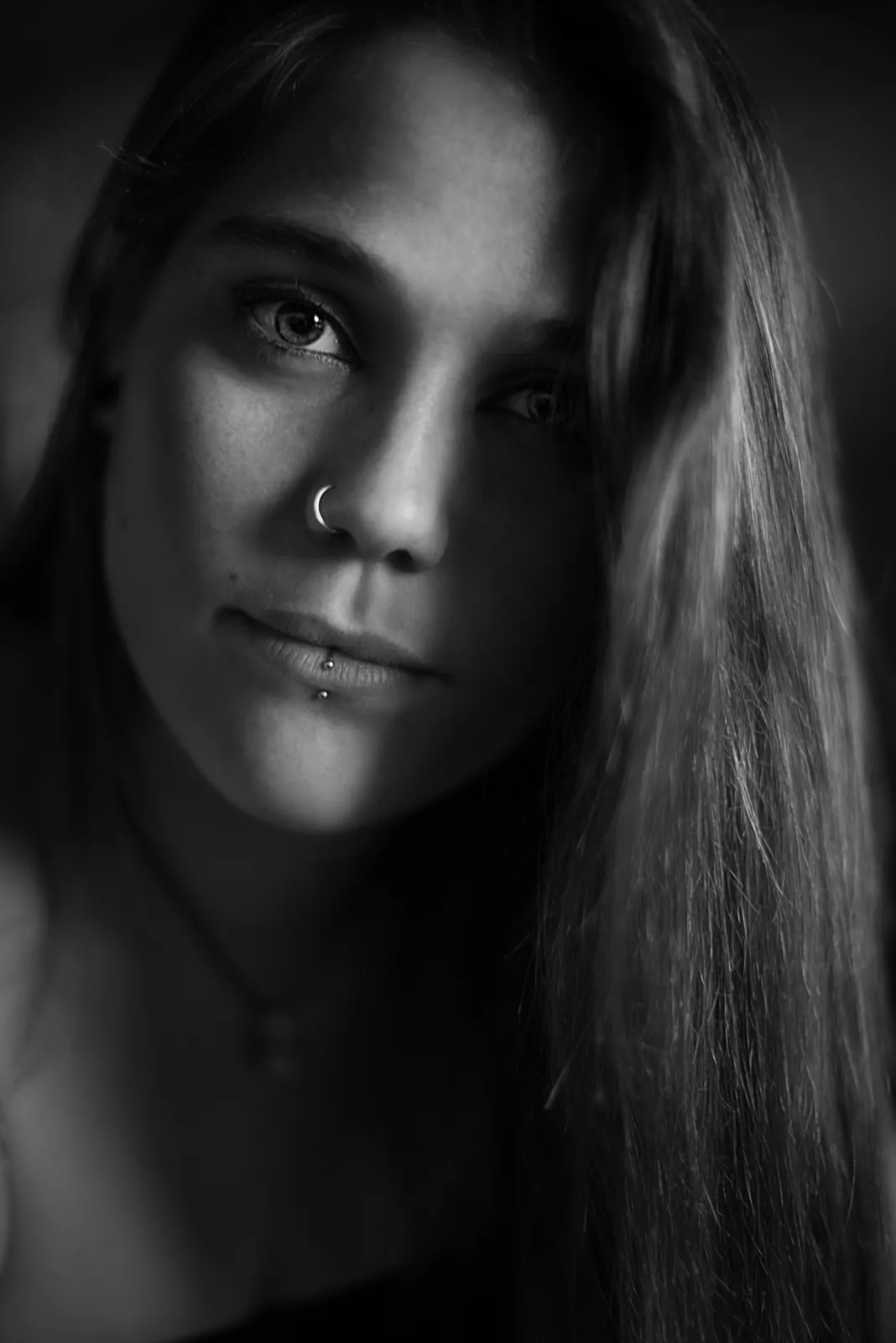 Black-and-white photograph: close-up portrait of a woman with long hair in soft side lighting.