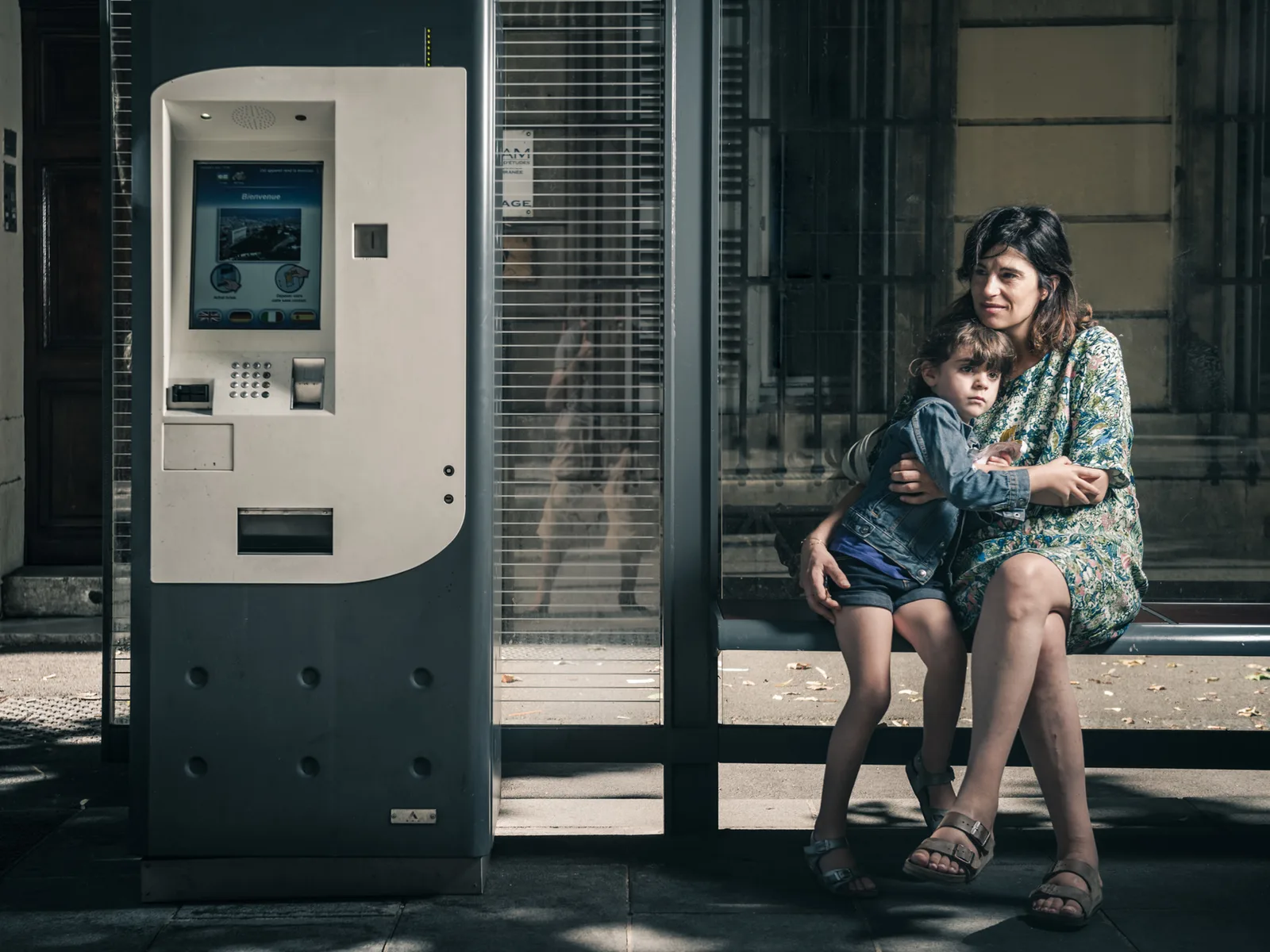 Woman seated beside a street ticket machine.
