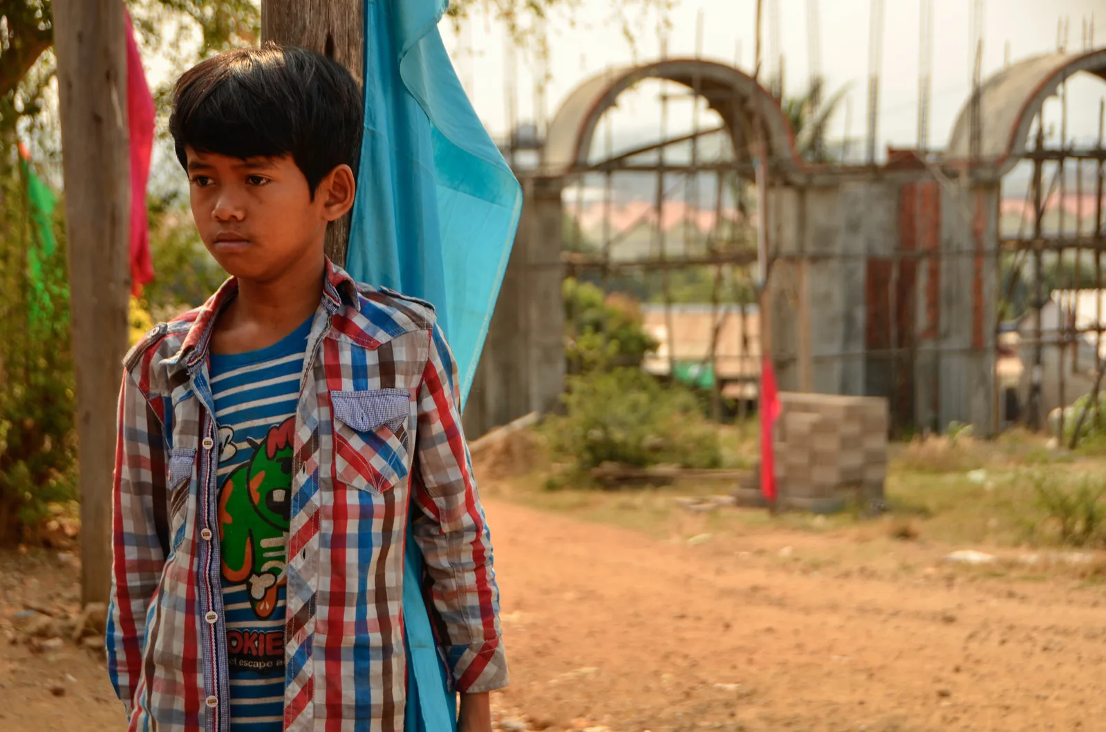 Child in a checked shirt beside the temple construction site.
