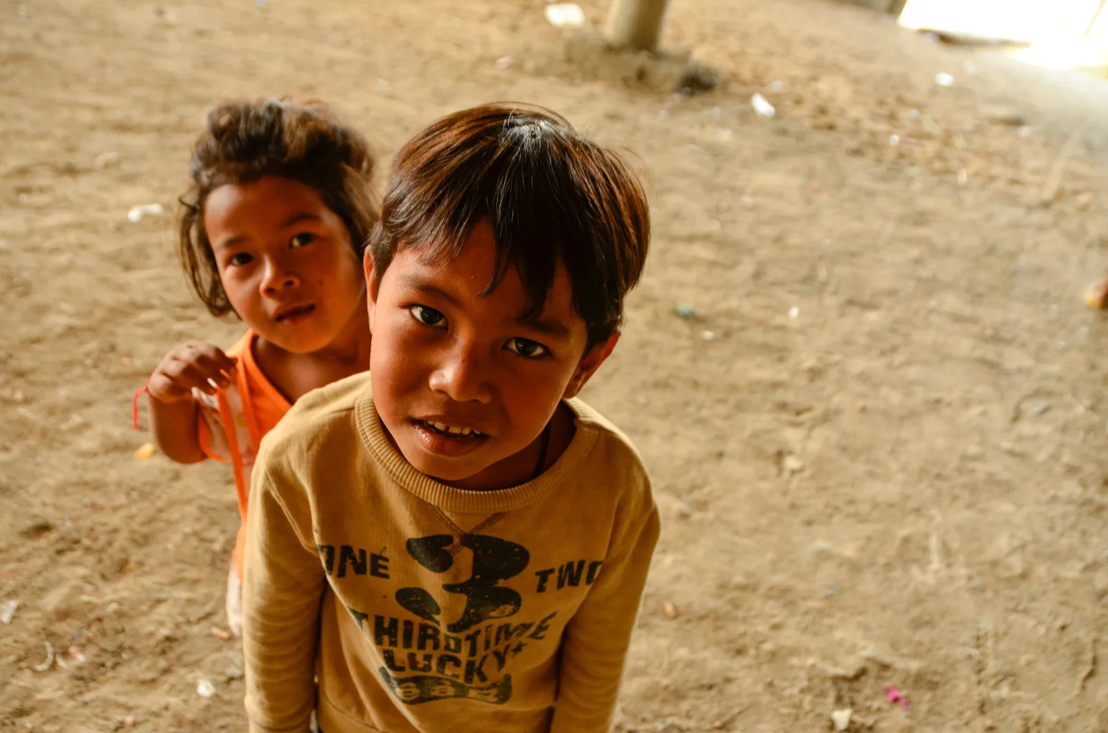 Two children facing the camera in a sunlit courtyard.