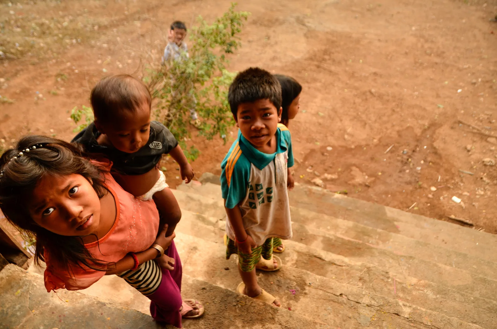 Children looking up toward the camera beside stone steps.