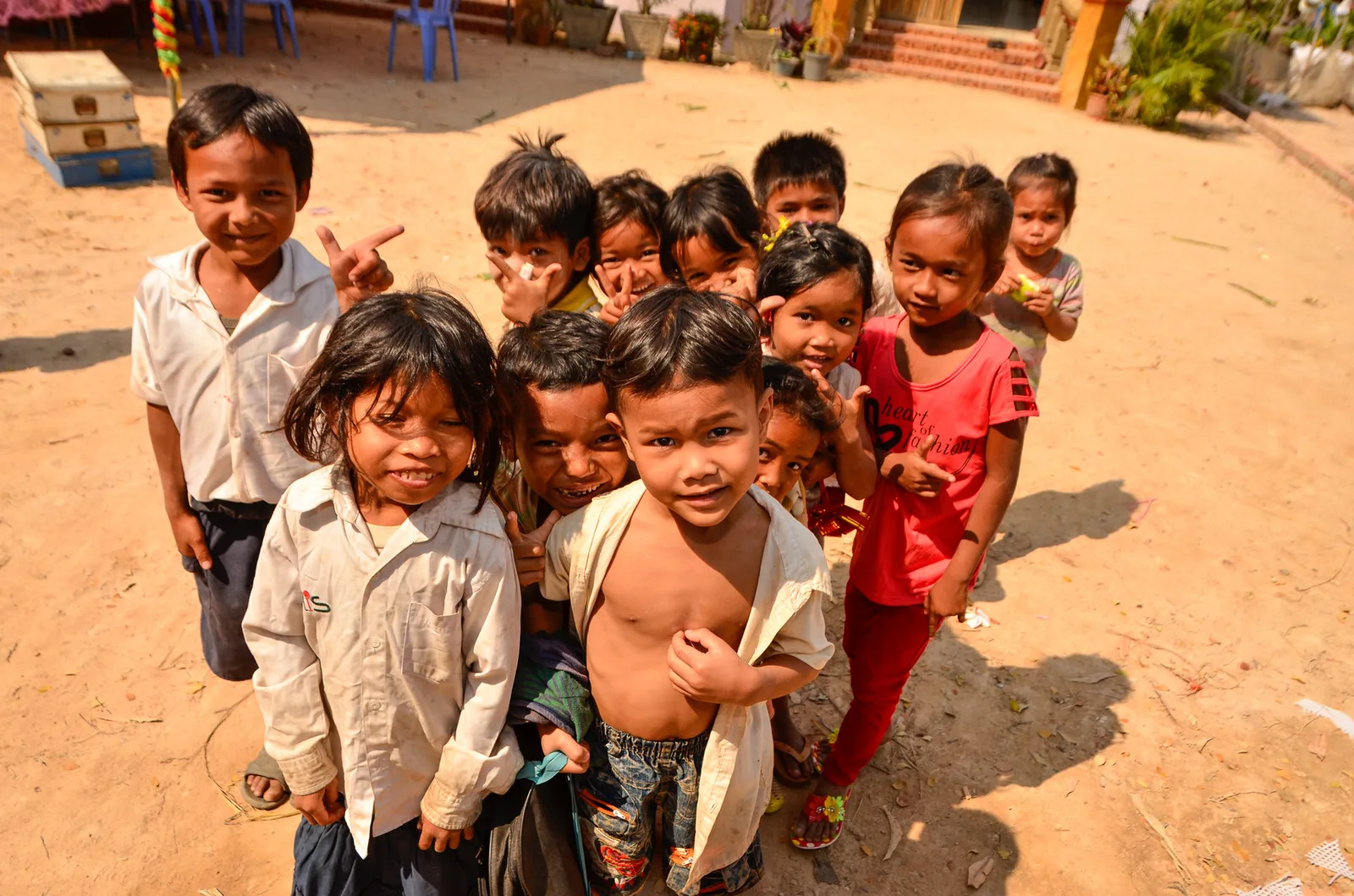Children gathered in a line on a sandy village path.